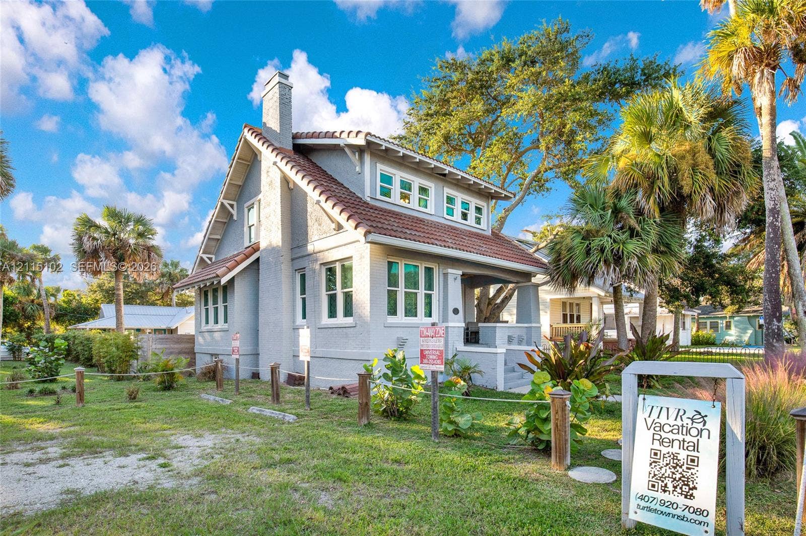 110 S Peninsula, New Smyrna Beach, FL 32169 Craftsman-style exterior featuring a clay-tiled roof, exterior stone chimney, multi-pane windows, and a covered front porch