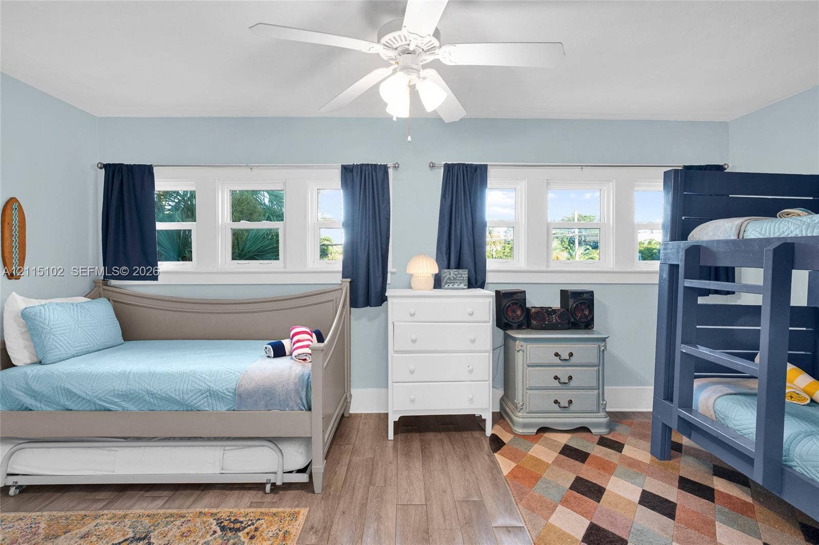 110 S Peninsula, New Smyrna Beach, FL 32169 Room featuring wood-finish flooring, dual sets of triple-pane windows, and a central ceiling fan with integrated lighting
