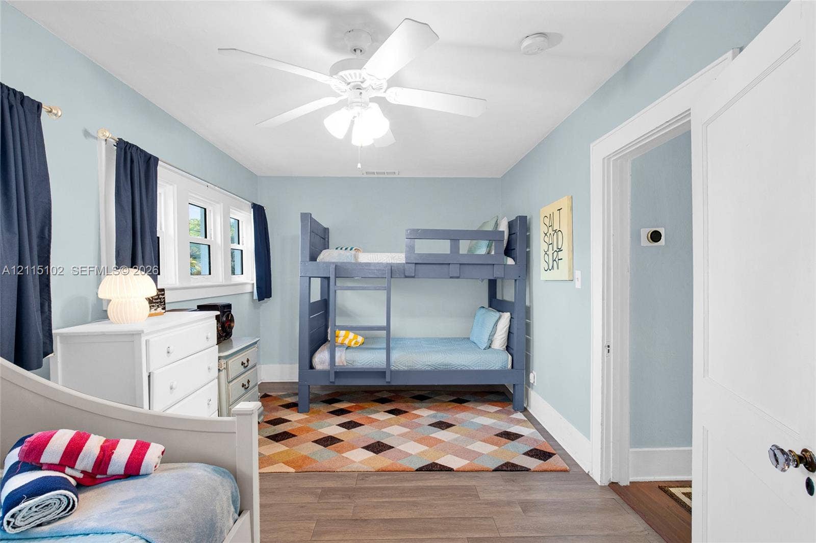 110 S Peninsula, New Smyrna Beach, FL 32169 Multi-pane window assembly, white ceiling-mounted fan with integrated light fixture, wood-finish flooring, and white interior door with metallic hardware