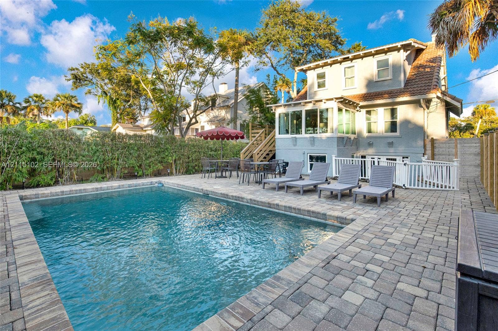 110 S Peninsula, New Smyrna Beach, FL 32169 In-ground swimming pool with stone-paver decking and white picket perimeter fencing