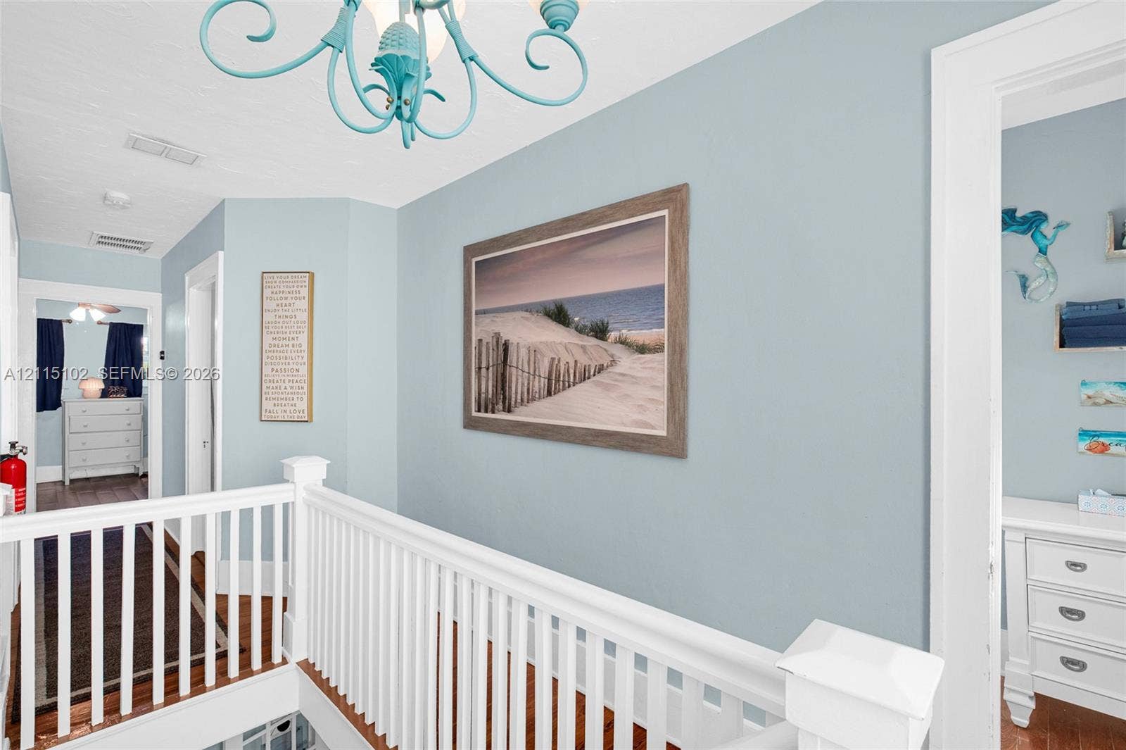 110 S Peninsula, New Smyrna Beach, FL 32169 Light blue painted walls, white wooden balustrade, wood-finish flooring, and decorative light fixture