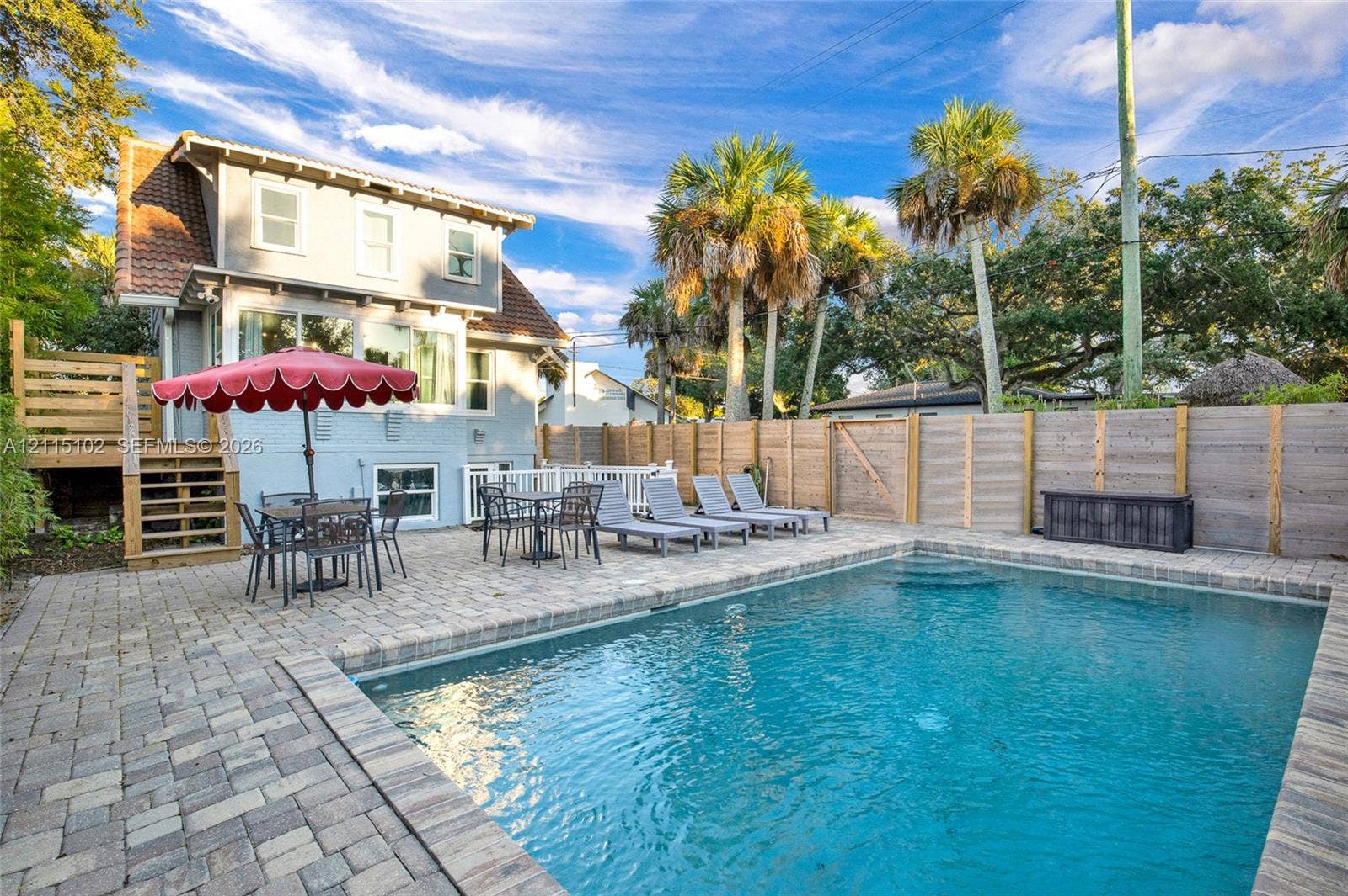 110 S Peninsula, New Smyrna Beach, FL 32169 Outdoor living space featuring an in-ground swimming pool, stone paver decking, wood privacy fencing, and elevated wood-framed stairs