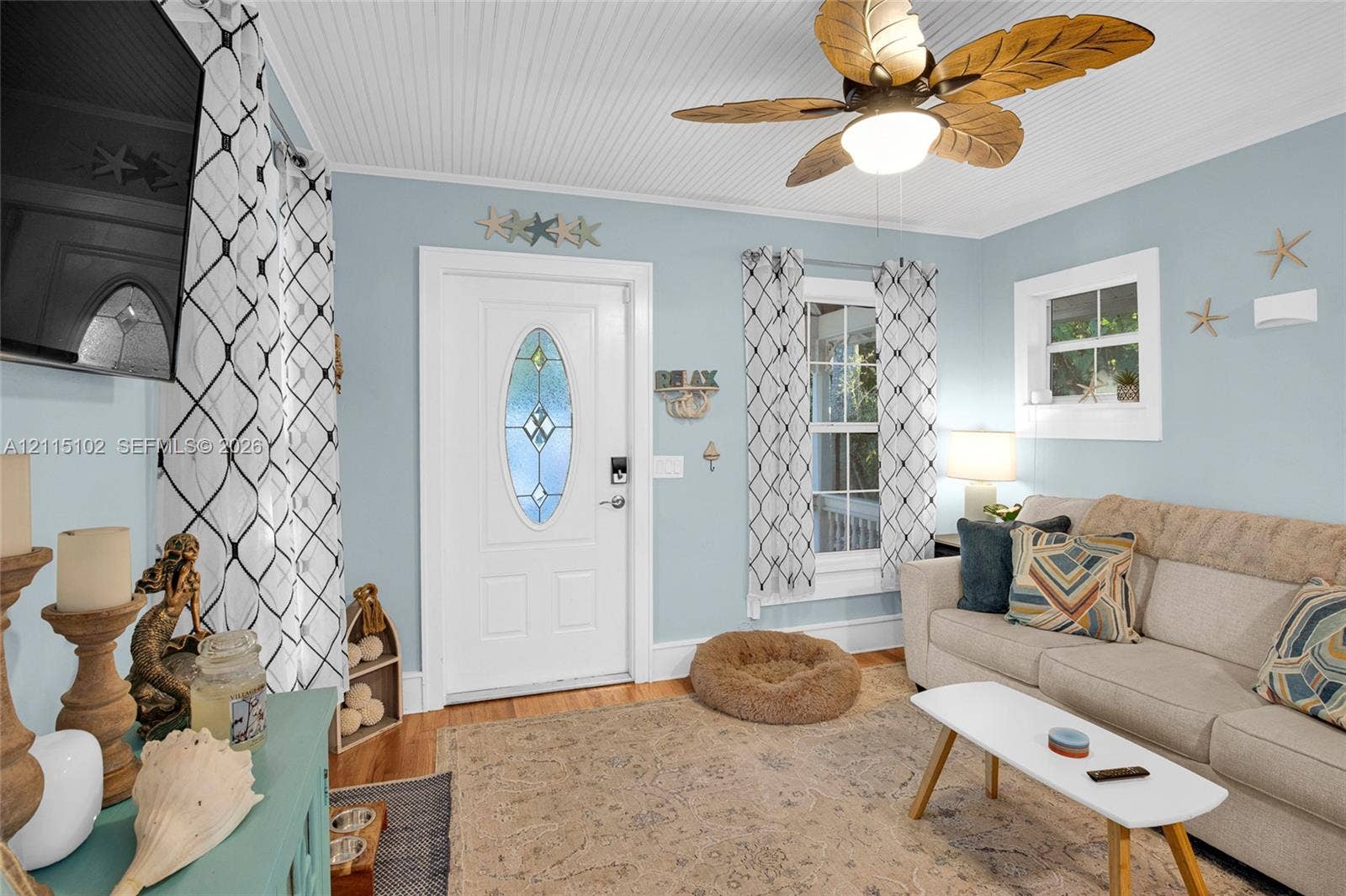 110 S Peninsula, New Smyrna Beach, FL 32169 Beaded board ceiling, ceiling fan with palm-leaf blades, wood flooring, and entry door with an oval glass insert