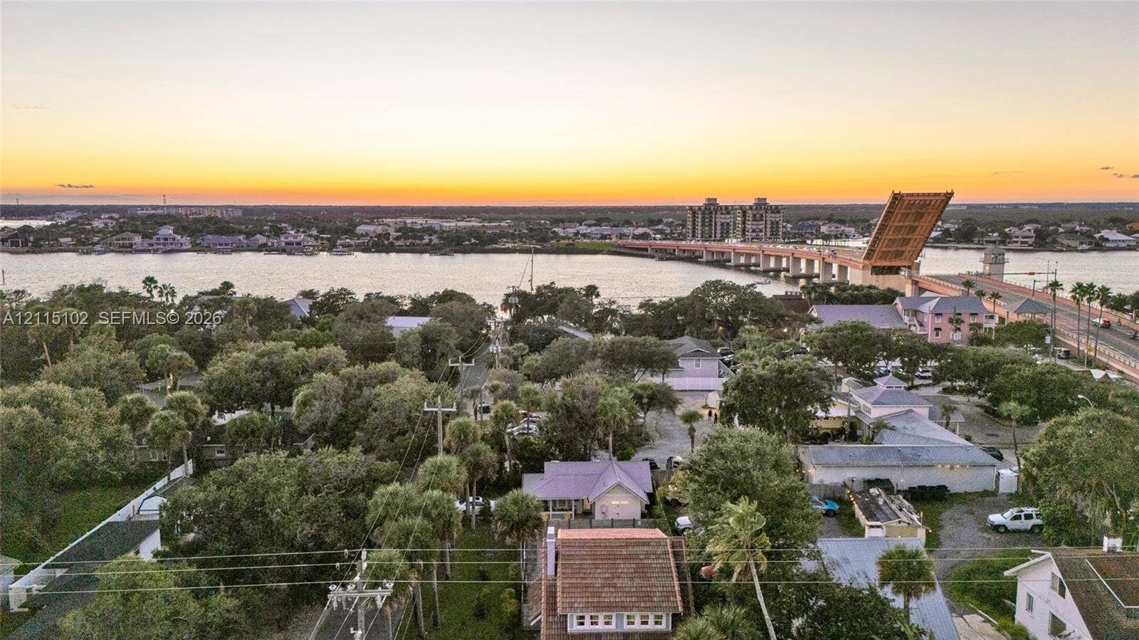 110 S Peninsula, New Smyrna Beach, FL 32169 Aerial perspective of the coastal landscape featuring a waterway, an open bascule bridge, mature palm trees, and dense foliage