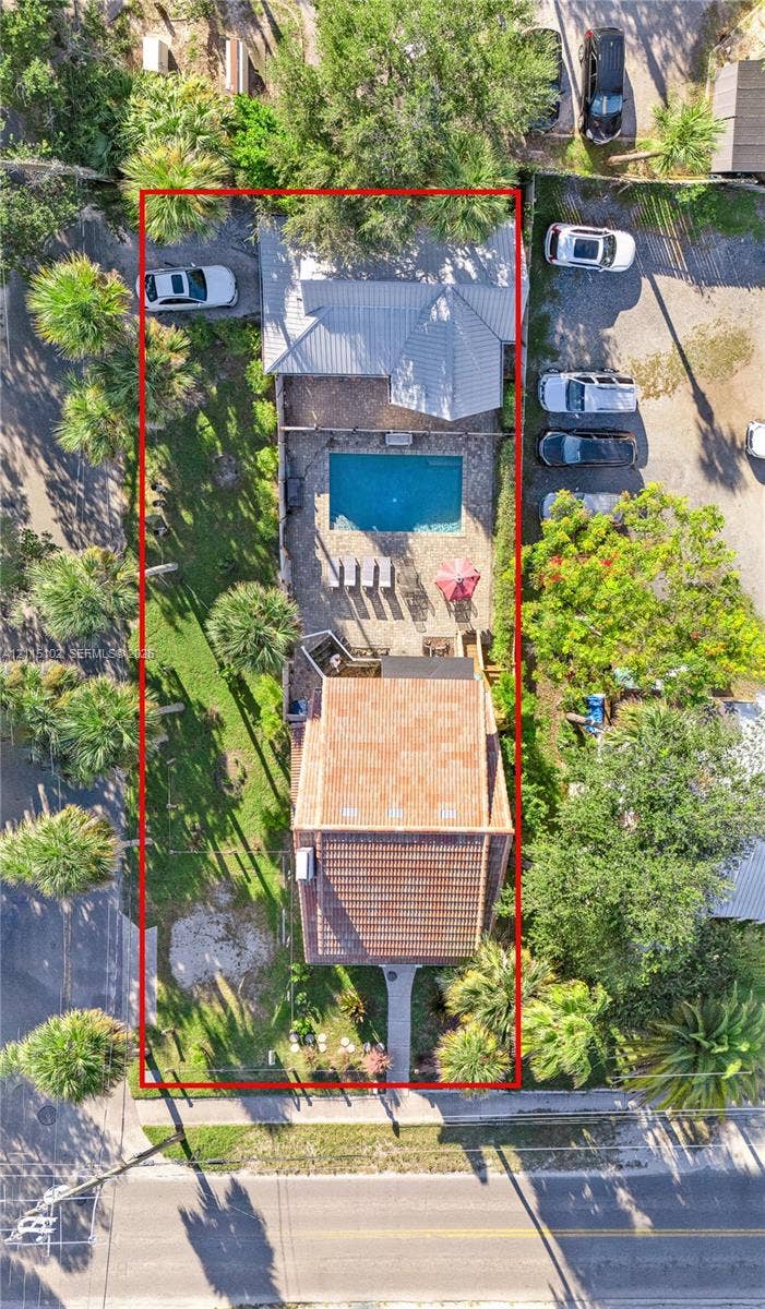 110 S Peninsula, New Smyrna Beach, FL 32169 Aerial view of property featuring a swimming pool, paved patio, tiled roof, and landscaped lawn with mature palm trees