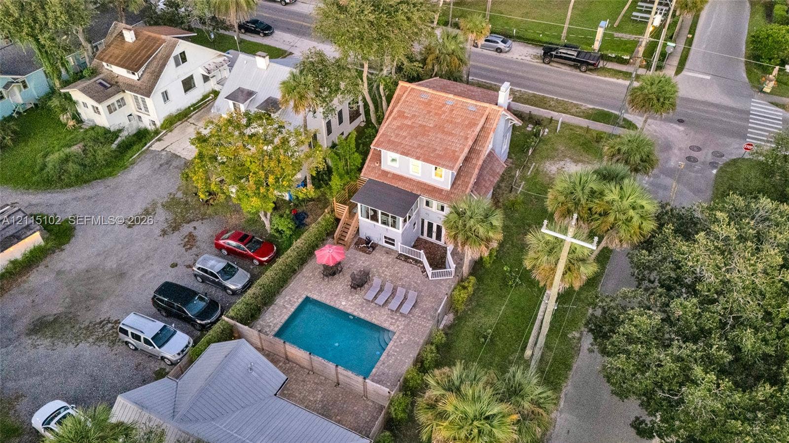 110 S Peninsula, New Smyrna Beach, FL 32169 Multi-story residence featuring a shingled roof, ground-level paved patio, built-in swimming pool, and mature palm trees