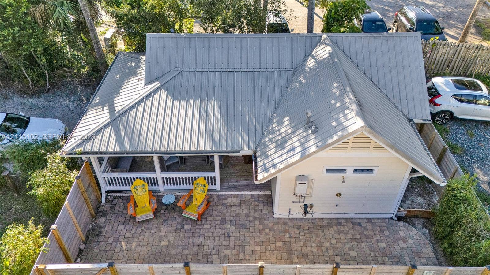 110 S Peninsula, New Smyrna Beach, FL 32169 Metal roof, covered porch with white railing, and a paver stone patio enclosed by a wood privacy fence