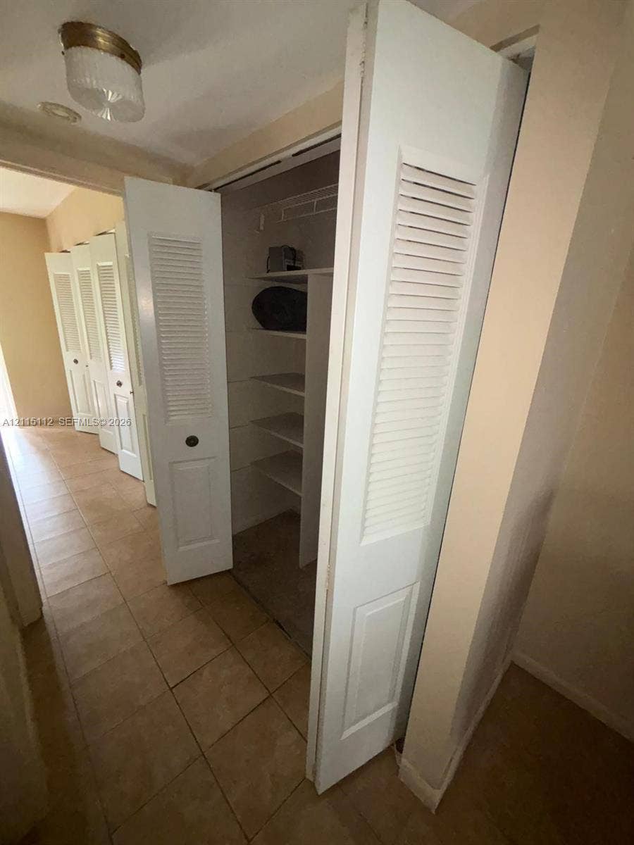 89 Andover D, #89, West Palm Beach, West Palm Beach, FL 33417 Multiple closets featuring white bi-fold louvered doors, tile flooring, and interior built-in shelving