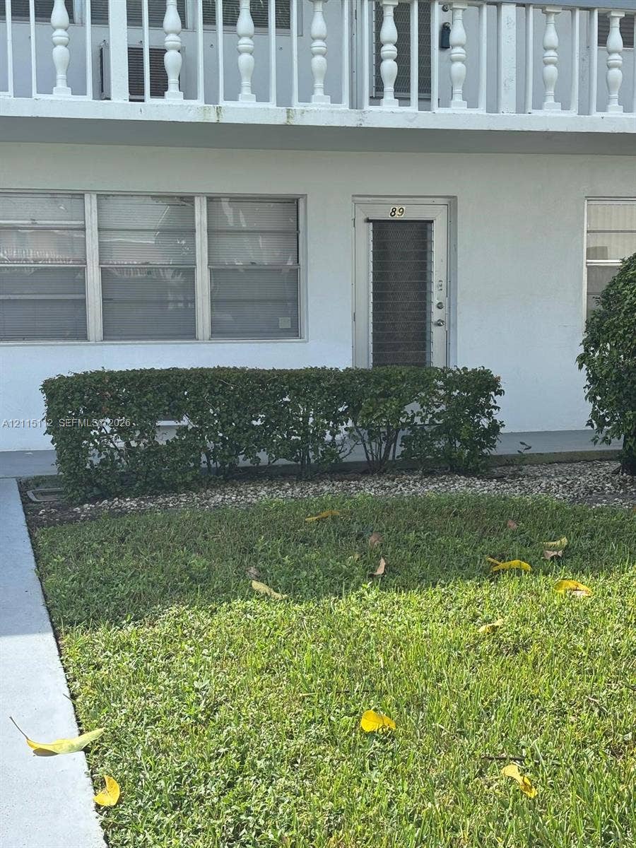 89 Andover D, #89, West Palm Beach, West Palm Beach, FL 33417 Exterior facade featuring horizontal sliding windows, a glass-paneled entry door, and a second-level balcony with decorative balusters
