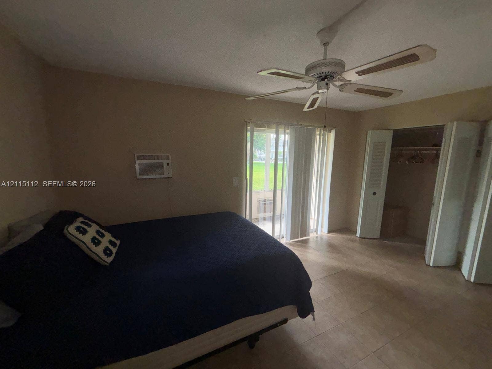 89 Andover D, #89, West Palm Beach, West Palm Beach, FL 33417 Neutral-toned room featuring tile flooring, a multi-blade ceiling fan, sliding glass doors, and a closet with bifold doors