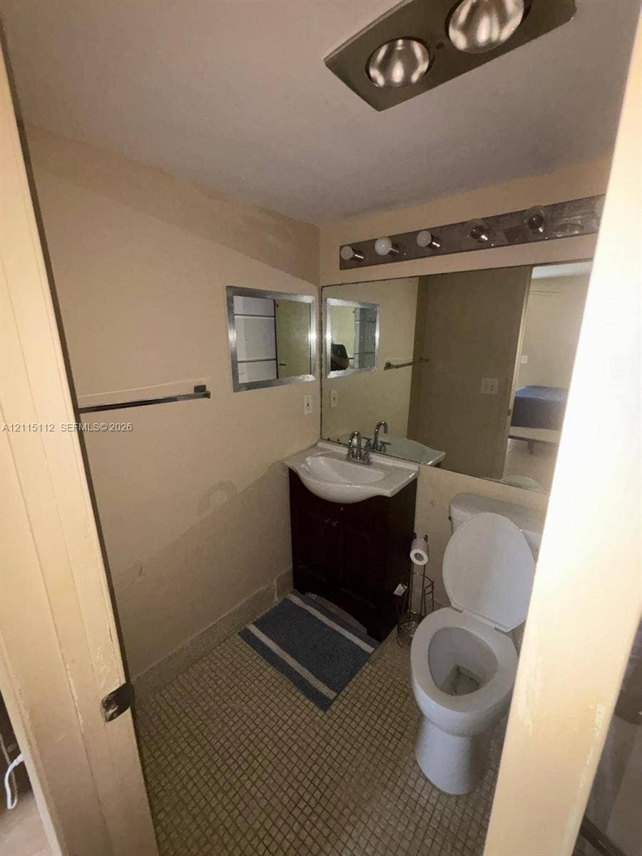 89 Andover D, #89, West Palm Beach, West Palm Beach, FL 33417 Bathroom featuring a vanity cabinet with a curved basin, wall-mounted mirror, multi-bulb vanity light, and tiled flooring