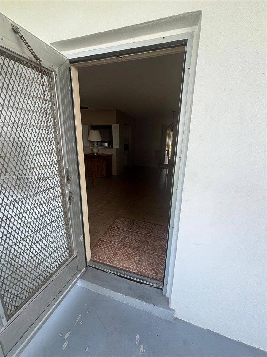 89 Andover D, #89, West Palm Beach, West Palm Beach, FL 33417 Metal security screen door featuring an integrated diamond-pattern mesh, installed in a white-trimmed doorway with tiled entry flooring