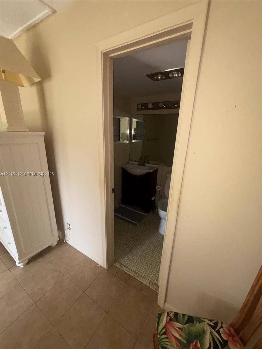 89 Andover D, #89, West Palm Beach, West Palm Beach, FL 33417 Bathroom featuring a dark-finish vanity with a white basin, a wall-mounted light fixture, and tile flooring