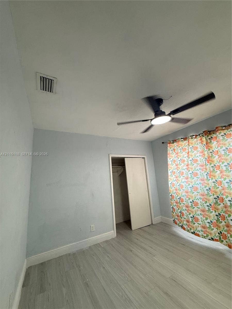 2816 SW 4th Place, #A, Fort Lauderdale, Fort Lauderdale, FL 33312 Room featuring wood-finish flooring, a matte black ceiling fan with integrated lighting, and a closet with a swinging door