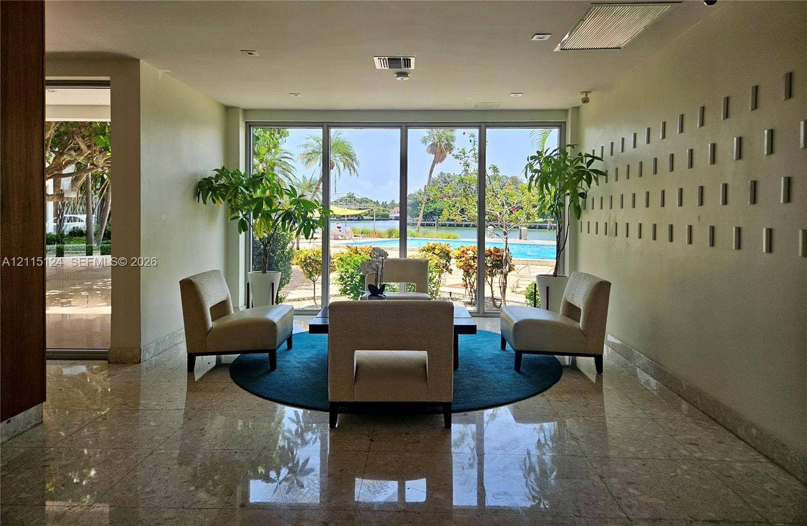 9102 W Bay Harbor Drive, #6-B, Bay Harbor Islands, Bay Harbor Islands, FL 33154 Floor-to-ceiling glass windows, polished stone flooring, and textured wall accents, complemented by an outdoor swimming pool and water frontage
