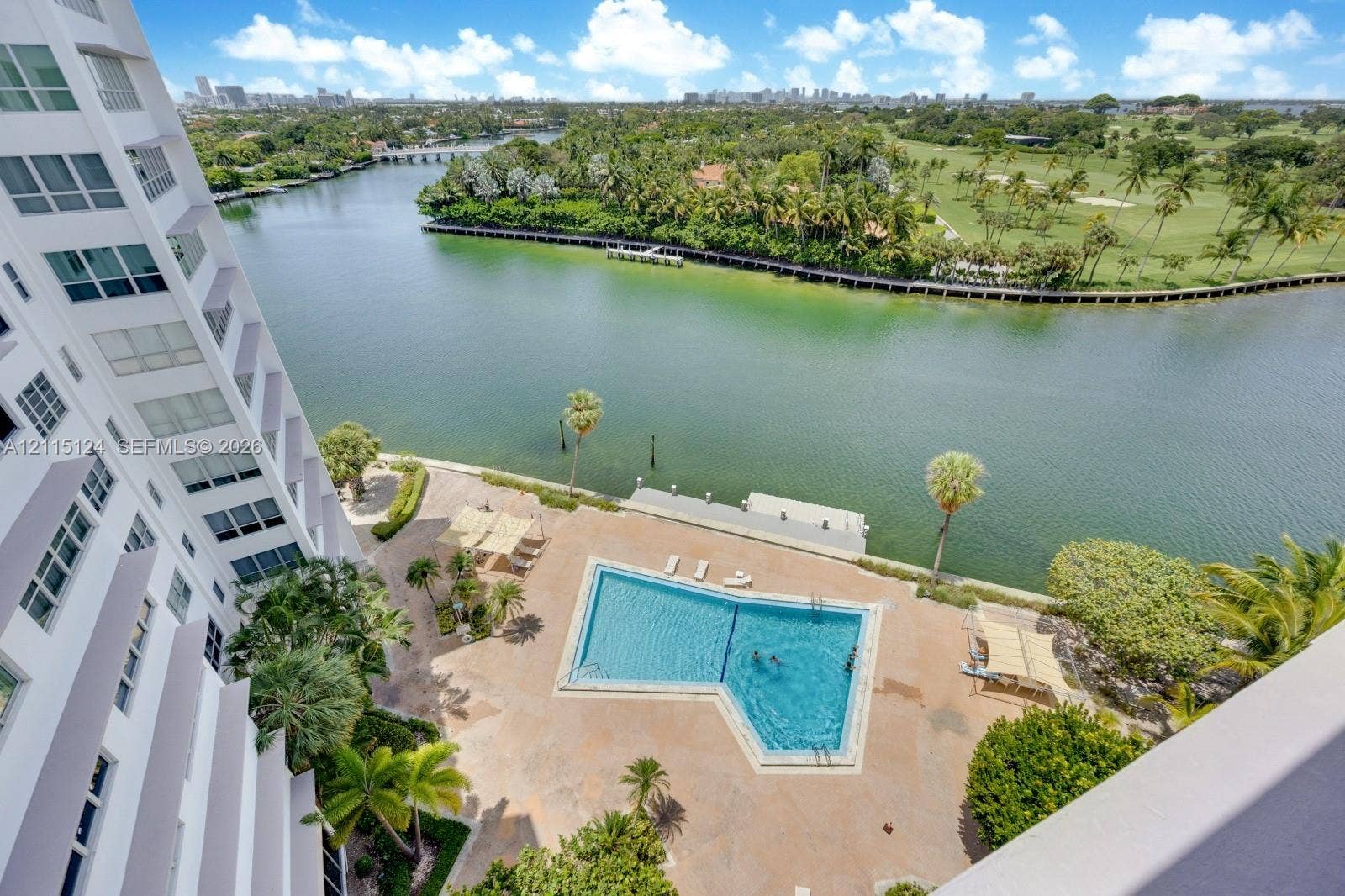9102 W Bay Harbor Drive, #6-B, Bay Harbor Islands, Bay Harbor Islands, FL 33154 Aerial perspective of the property grounds featuring a swimming pool, paved deck, water frontage, and lush landscaping