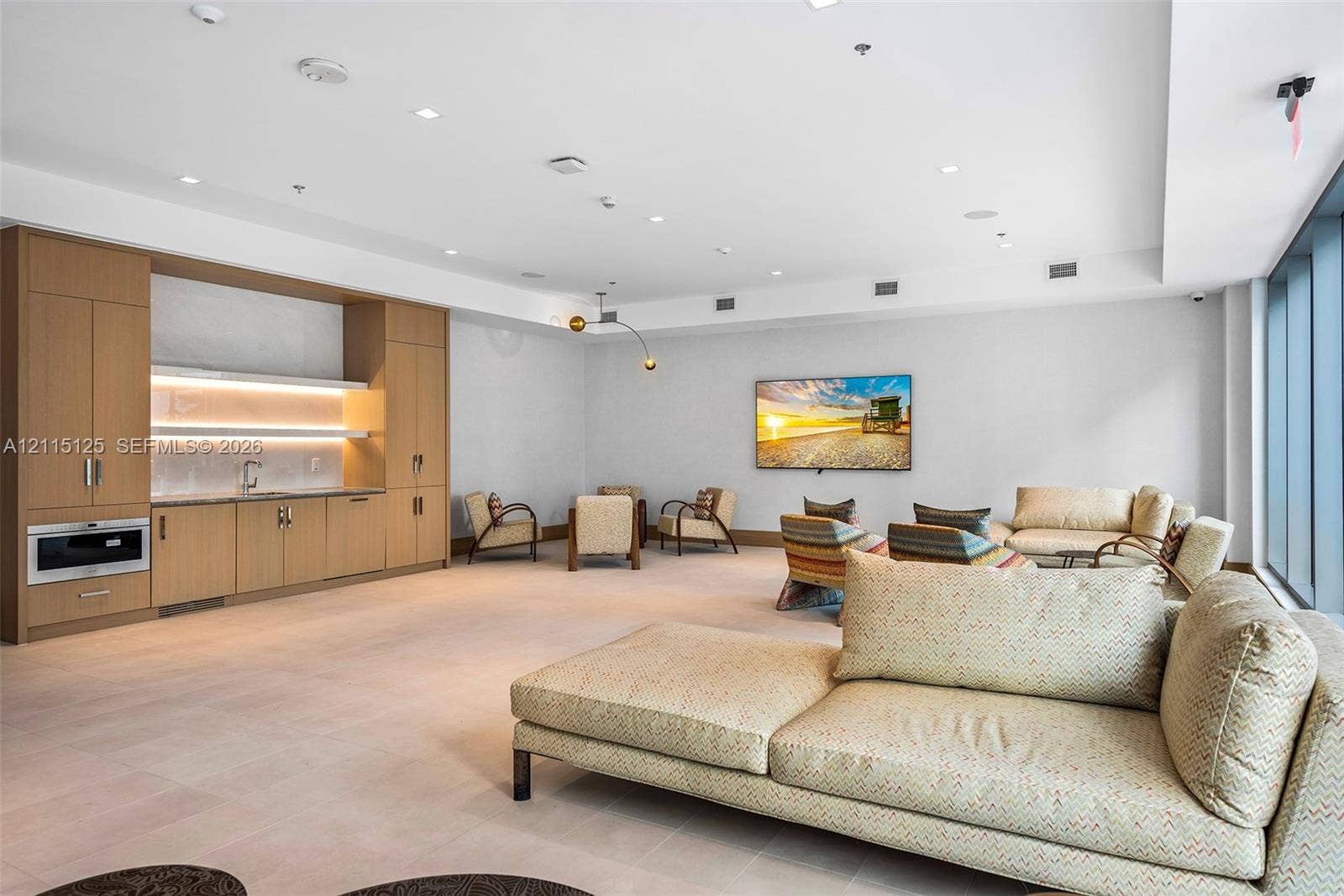Common area featuring built-in wood-finish cabinetry, integrated under-cabinet lighting, stainless steel microwave, stone-finish countertops, and floor-to-ceiling windows