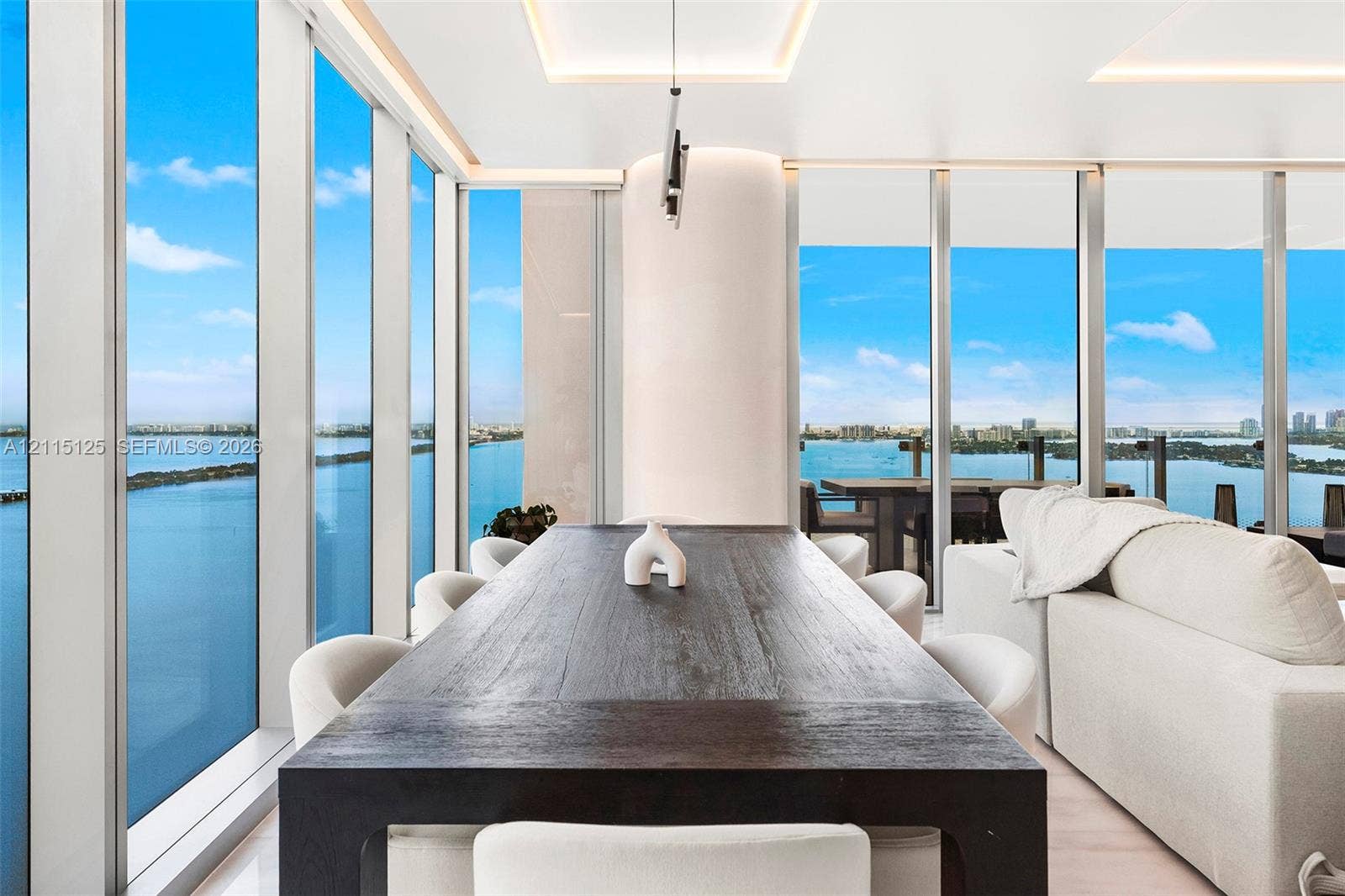 Floor-to-ceiling glass walls, recessed cove lighting, and expansive water scenery