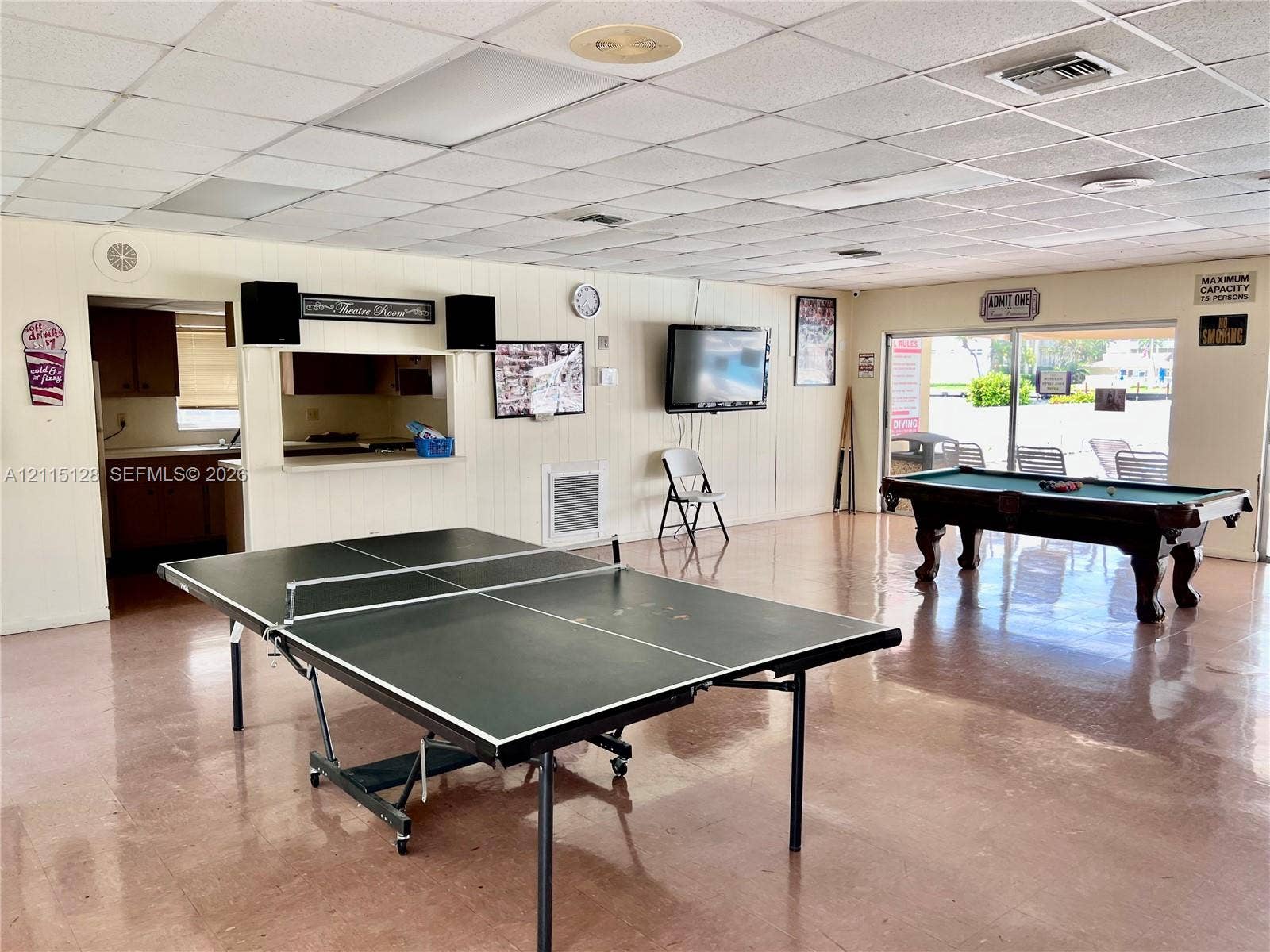 1817 S Ocean Drive, #426, Hallandale Beach, FL 33009 Open-concept recreational space featuring panelled walls, tile flooring, a drop ceiling with recessed lighting, and an integrated kitchenette pass-through window