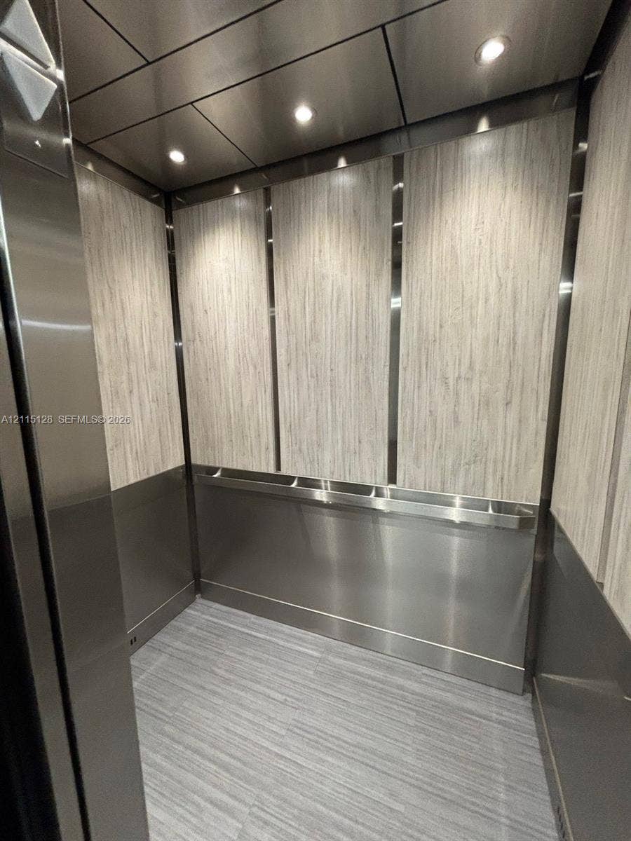 1817 S Ocean Drive, #426, Hallandale Beach, FL 33009 Elevator cab featuring vertical wood-finish wall paneling, stainless steel wainscoting and trim, recessed ceiling lighting, and tile flooring