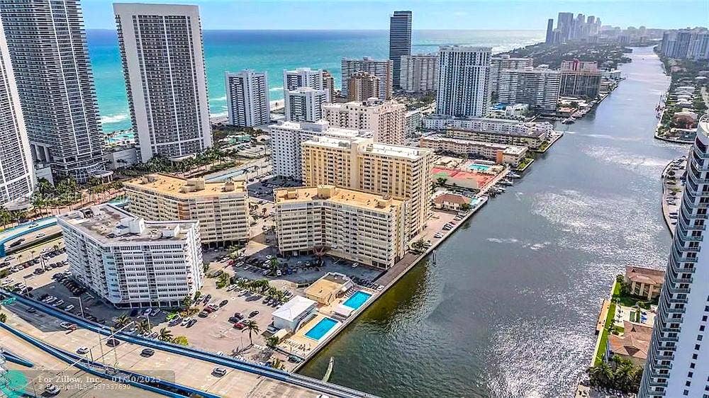 1817 S Ocean Drive, #426, Hallandale Beach, FL 33009 Aerial perspective of a high-rise residential complex featuring waterfront access, swimming pools, paved surface parking, and proximity to the Atlantic Ocean