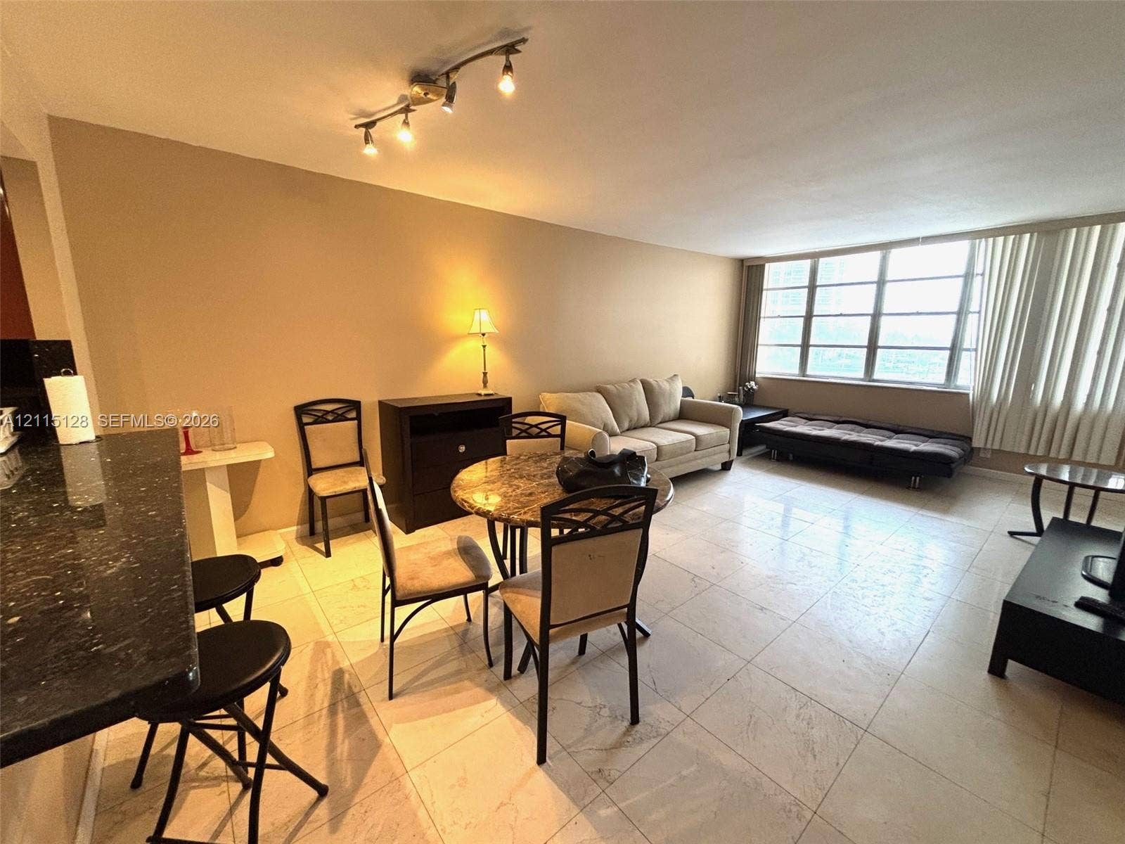 1817 S Ocean Drive, #426, Hallandale Beach, FL 33009 Open floor plan featuring large format tile flooring, a breakfast bar with dark stone countertop, and an expansive window wall
