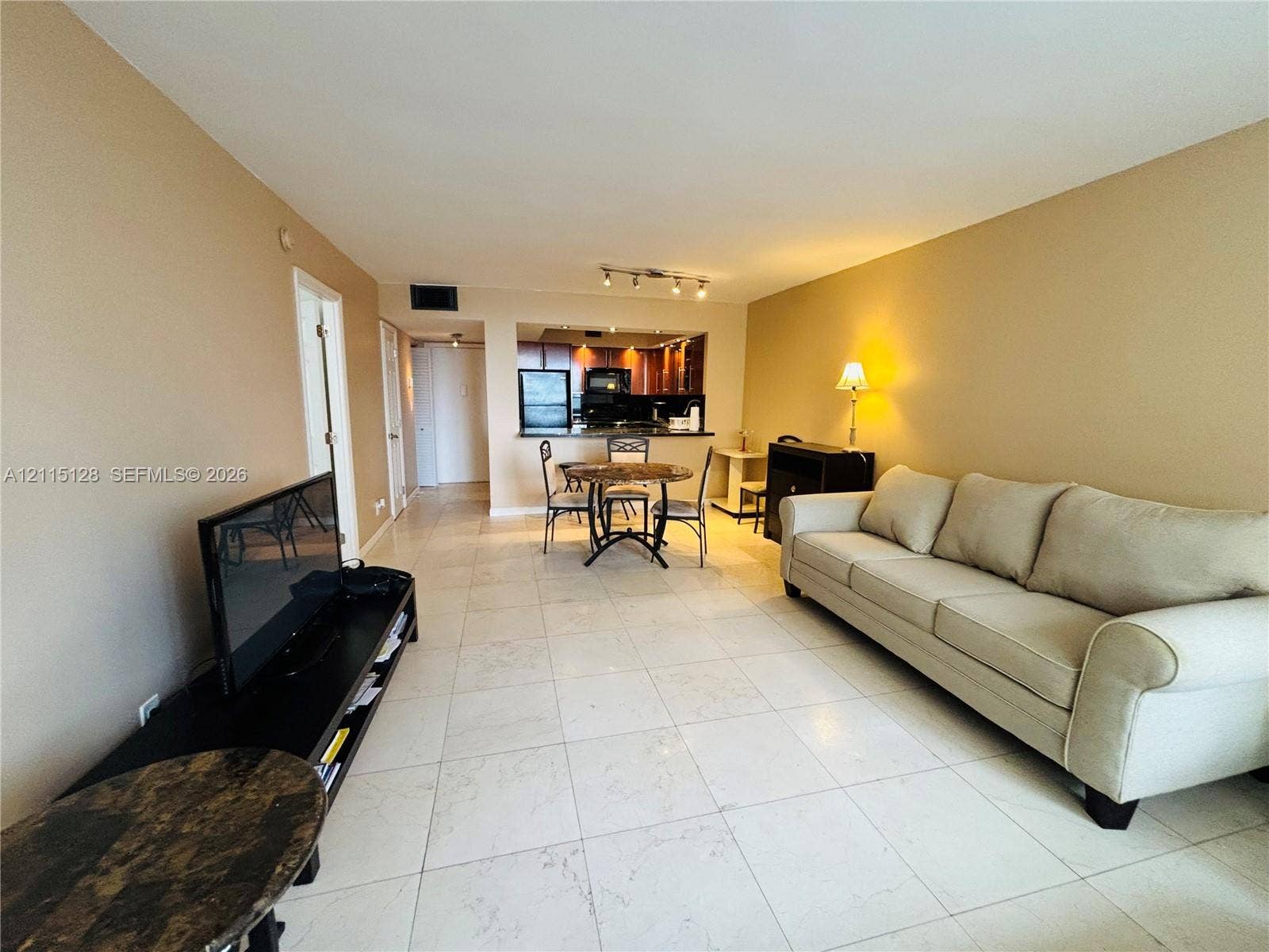 1817 S Ocean Drive, #426, Hallandale Beach, FL 33009 Interior featuring large-format light-toned tile flooring, recessed kitchen cabinetry, track lighting, and a kitchen pass-through opening