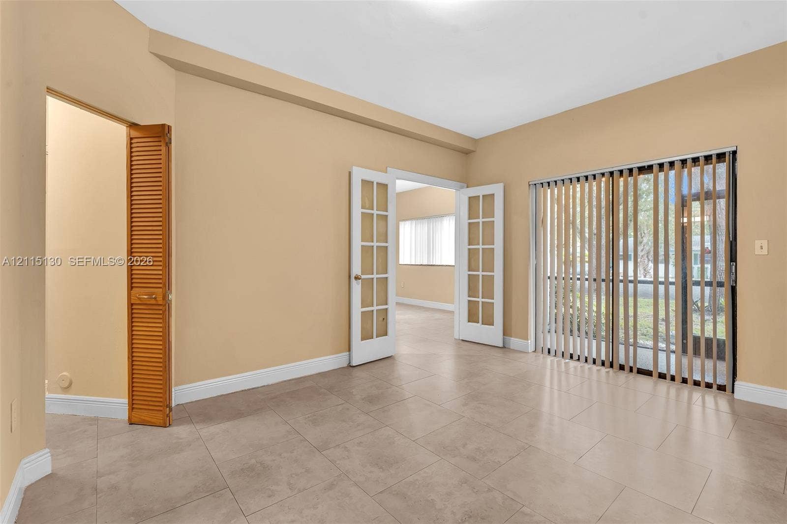 2445 SW 18th Terrace, #412, Fort Lauderdale, FL 33315 Neutral-tone tile flooring, French doors with glass panes, vertical blinds, and a louvered bi-fold closet door