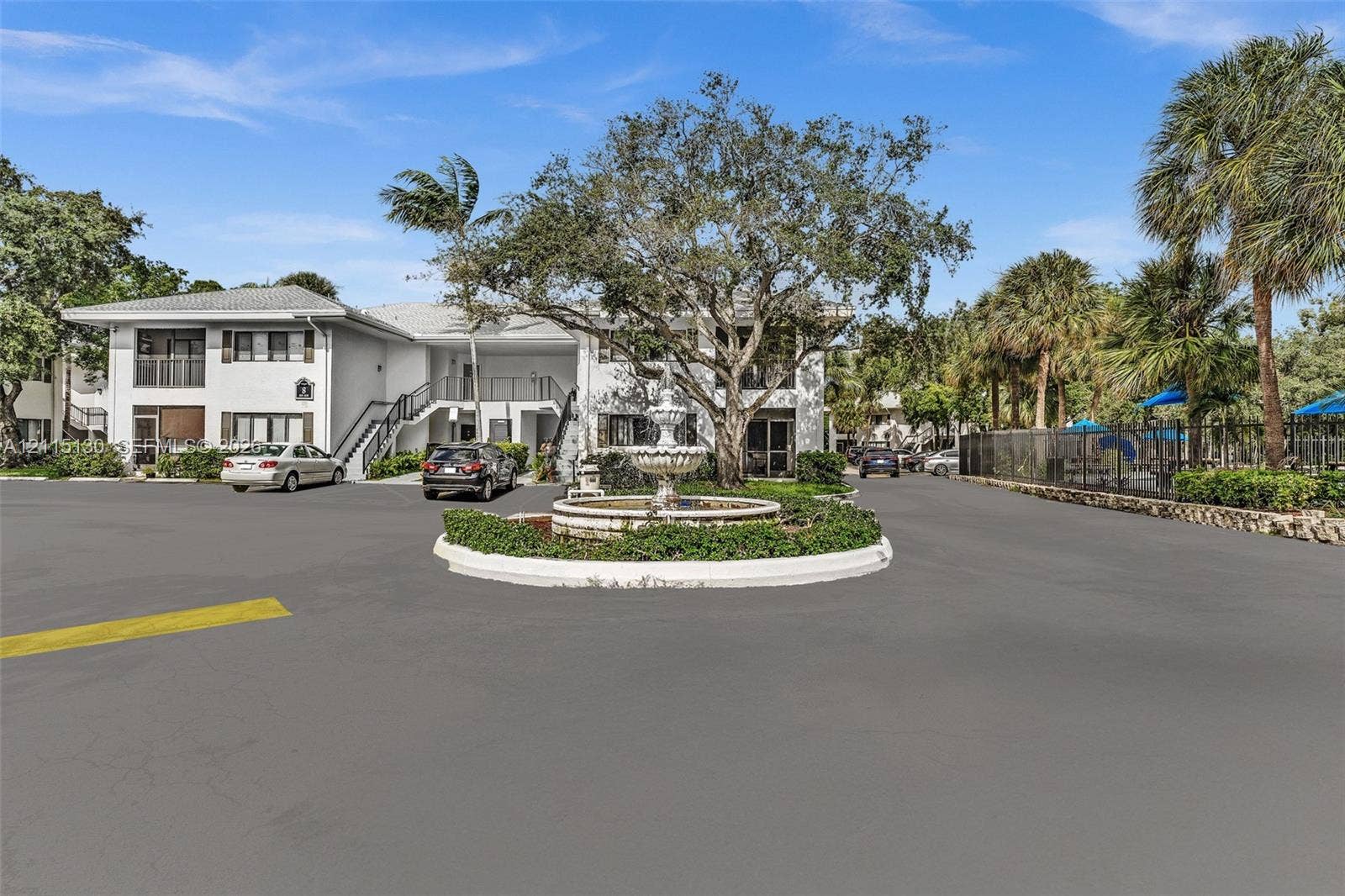 2445 SW 18th Terrace, #412, Fort Lauderdale, FL 33315 Exterior perspective featuring multi-story architecture, a central decorative stone fountain, manicured landscaping, and mature canopy trees
