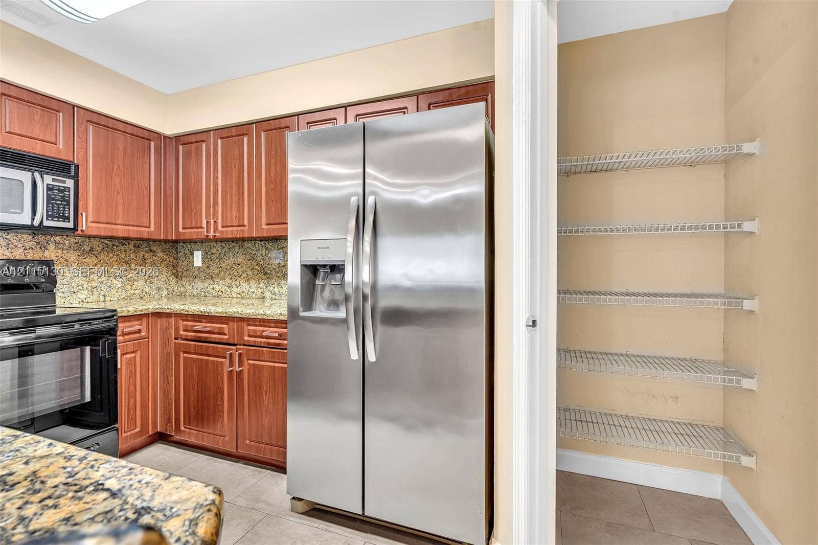 2445 SW 18th Terrace, #412, Fort Lauderdale, FL 33315 Kitchen featuring wood cabinetry, stone-surface countertops, stainless steel appliances, and a built-in wire shelving pantry