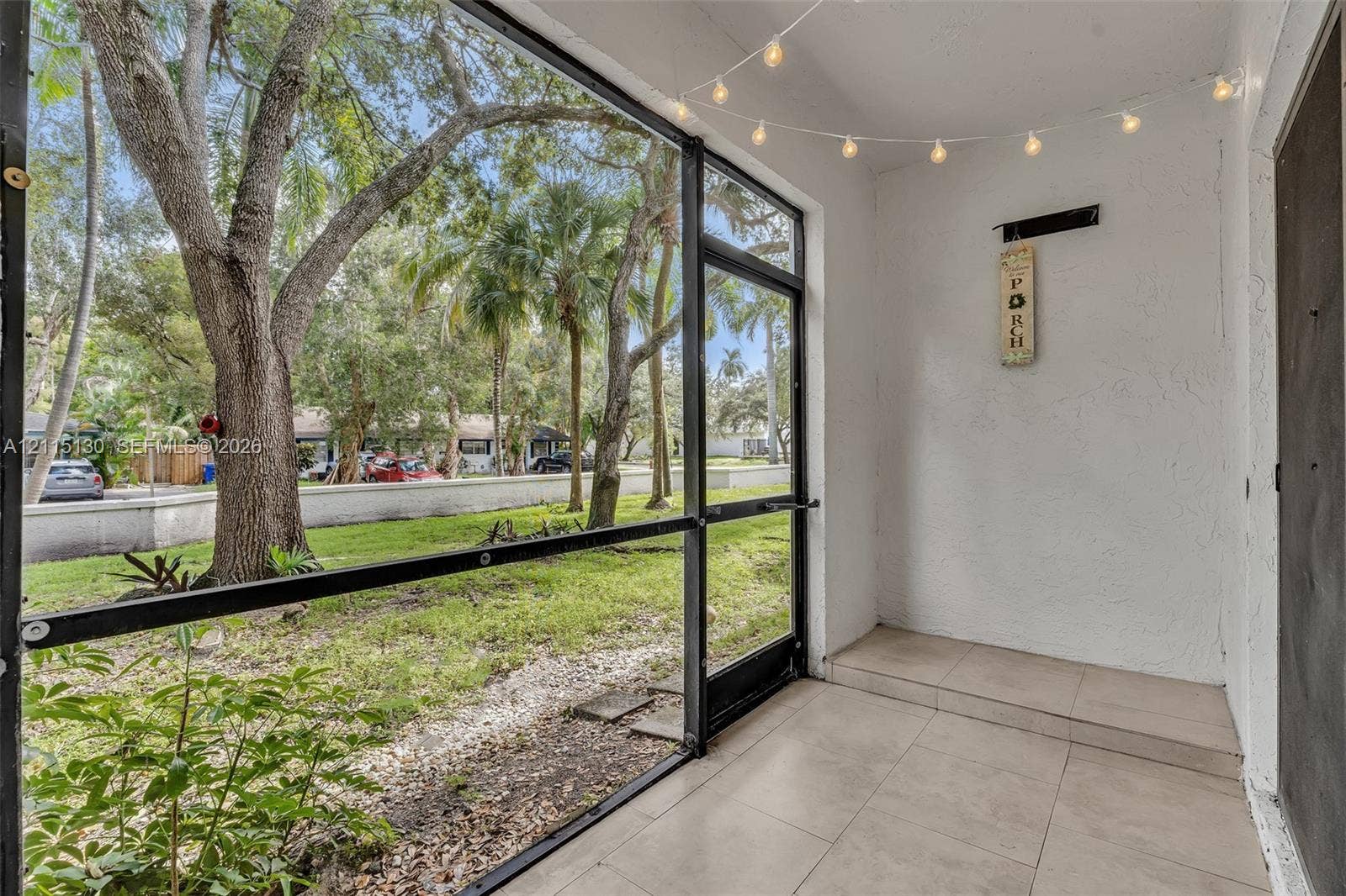 2445 SW 18th Terrace, #412, Fort Lauderdale, FL 33315 Screened patio featuring ceramic tile flooring, textured wall finishes, and black aluminum framing