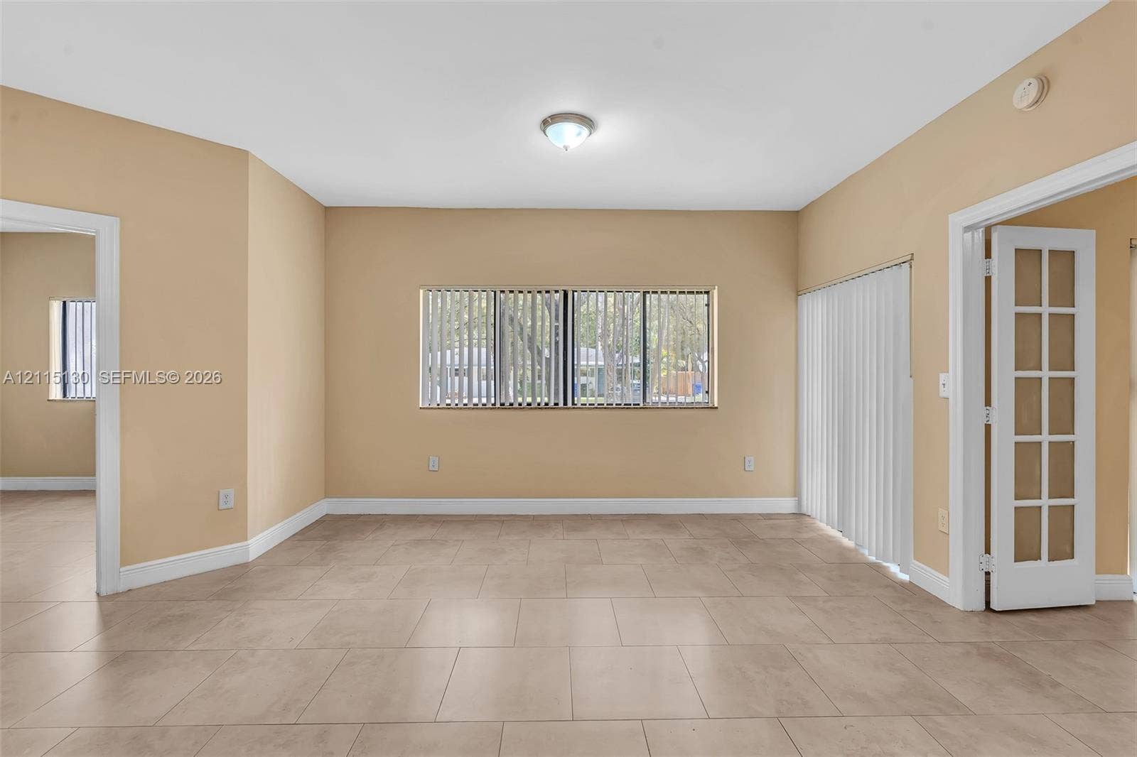 2445 SW 18th Terrace, #412, Fort Lauderdale, FL 33315 Neutral-toned tile flooring, horizontal blinds, vertical sliding blinds, and a white French door with glass panels