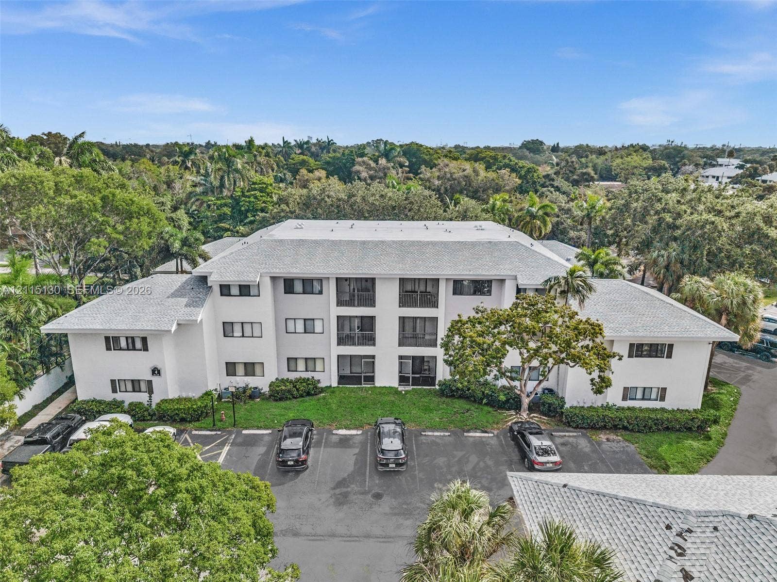2445 SW 18th Terrace, #412, Fort Lauderdale, FL 33315 Three-story multi-unit structure featuring a light-toned stucco exterior, a hip roof with asphalt shingles, private balconies, and dedicated surface parking