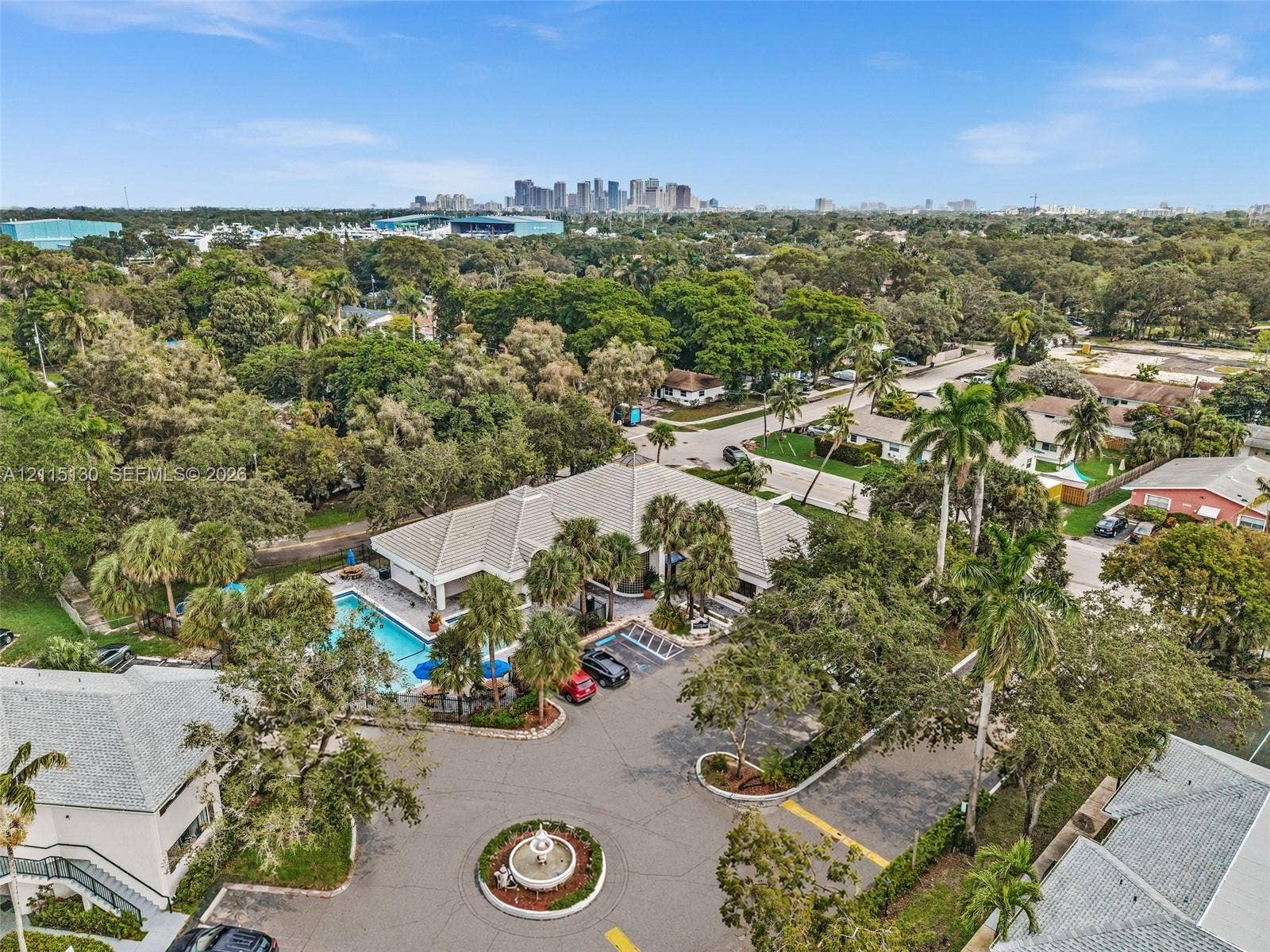2445 SW 18th Terrace, #412, Fort Lauderdale, FL 33315 Aerial perspective featuring a central fountain, swimming pool with deck area, mature landscaping, and an urban skyline backdrop