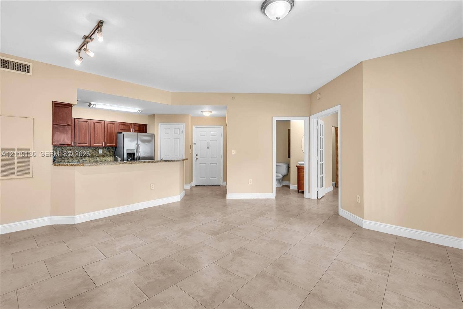 2445 SW 18th Terrace, #412, Fort Lauderdale, FL 33315 Open-concept interior featuring large-format tile flooring, kitchen with granite countertops and wood cabinetry, stainless steel refrigerator, and recessed track lighting