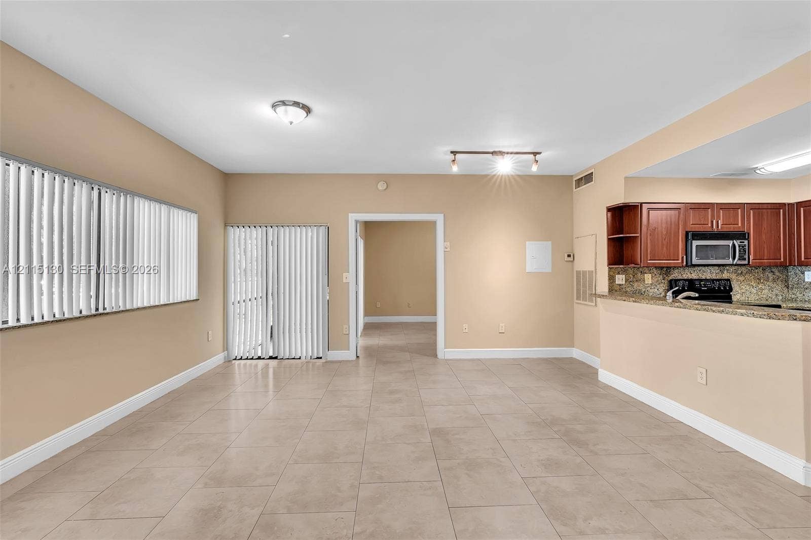 2445 SW 18th Terrace, #412, Fort Lauderdale, FL 33315 Large-format tile flooring, kitchen featuring wood-finish cabinetry, stone-surface countertops, track lighting, and sliding glass door