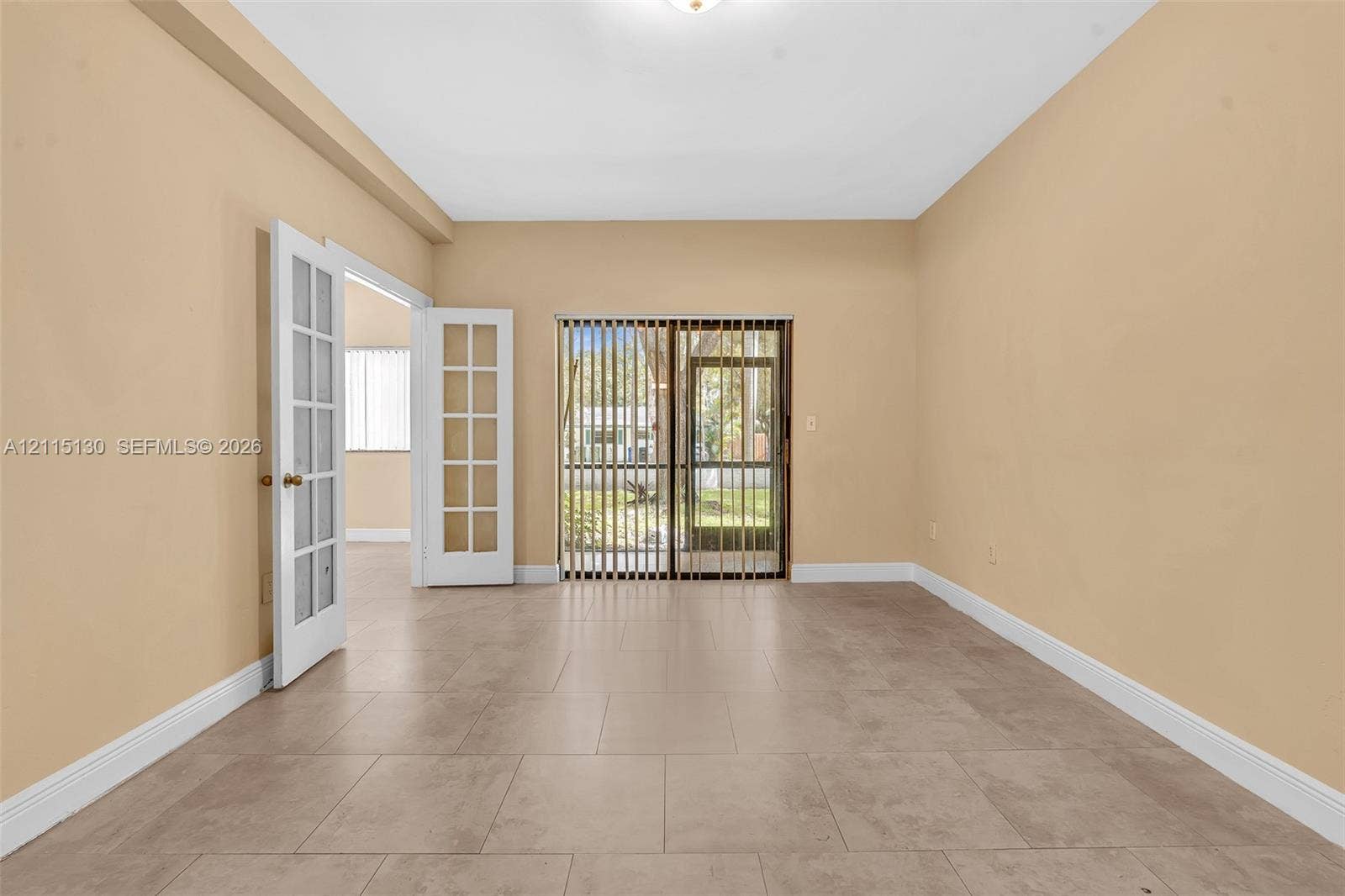 2445 SW 18th Terrace, #412, Fort Lauderdale, FL 33315 Interior space featuring neutral wall paint, large-format tile flooring, white-framed French doors, and sliding glass doors with vertical blinds