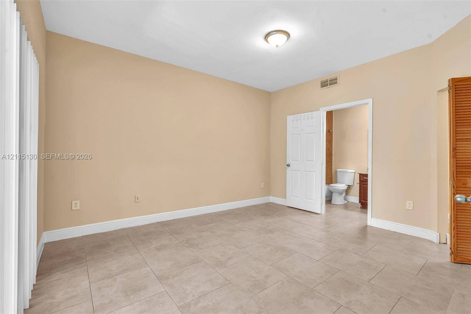 2445 SW 18th Terrace, #412, Fort Lauderdale, FL 33315 Neutral-toned interior room featuring large-format ceramic tile flooring, a six-panel interior door, and a wooden bi-fold door
