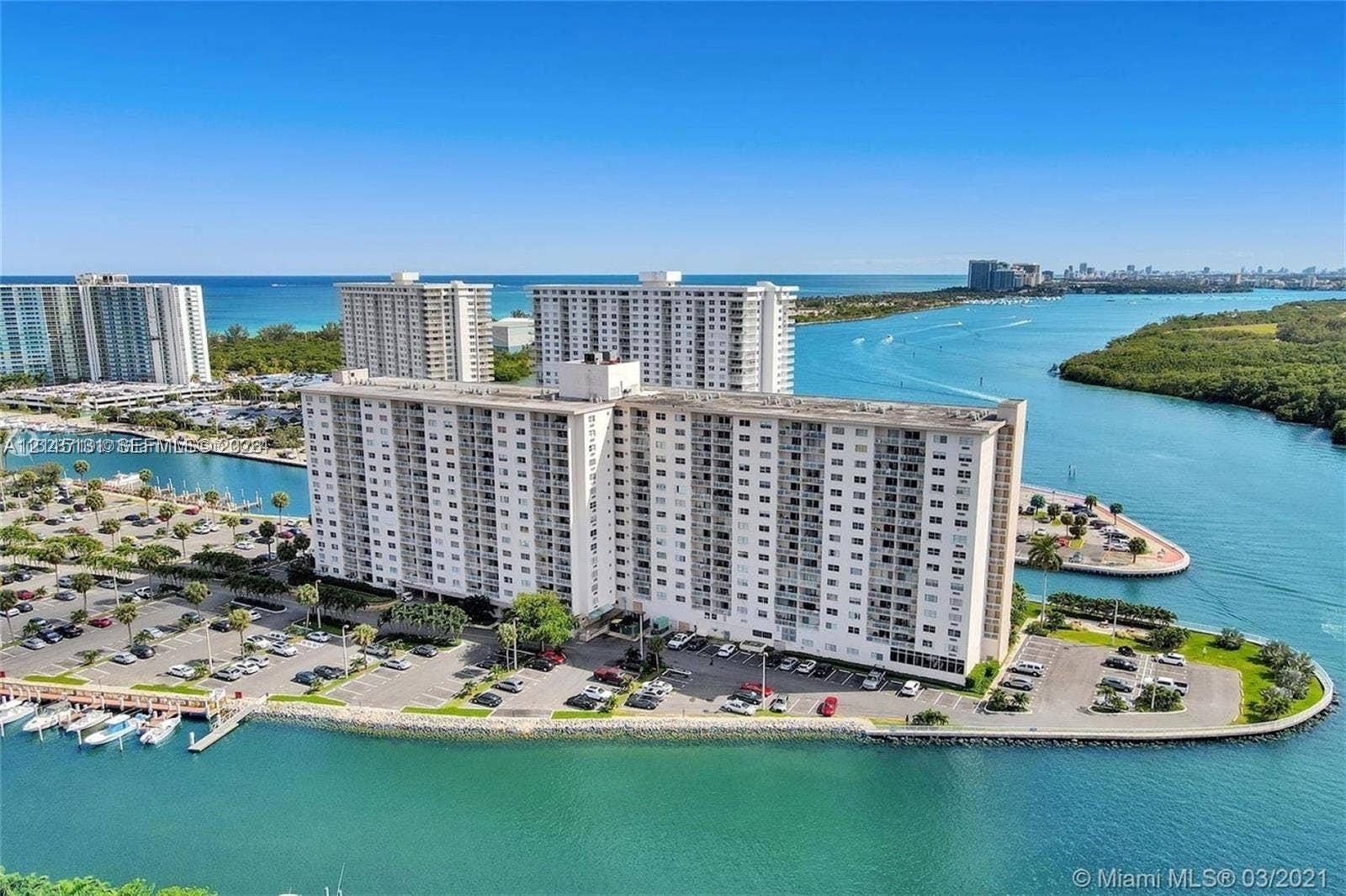 400 Kings Point Drive, #317, Sunny Isles Beach, FL 33160 High-rise residential building situated on a peninsula with expansive water frontage, boat docks, and surface parking