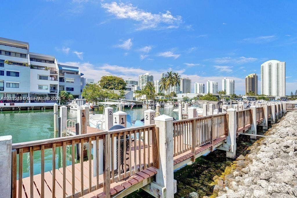 400 Kings Point Drive, #317, Sunny Isles Beach, FL 33160 Waterfront boat dock featuring individual slip numbering, wooden decking, and a protective railing