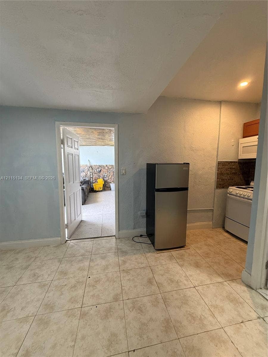 2816 SW 4th Place, #B, Fort Lauderdale, Fort Lauderdale, FL 33312 Kitchenette featuring tile flooring, stainless steel refrigerator, white electric range, and integrated cabinetry