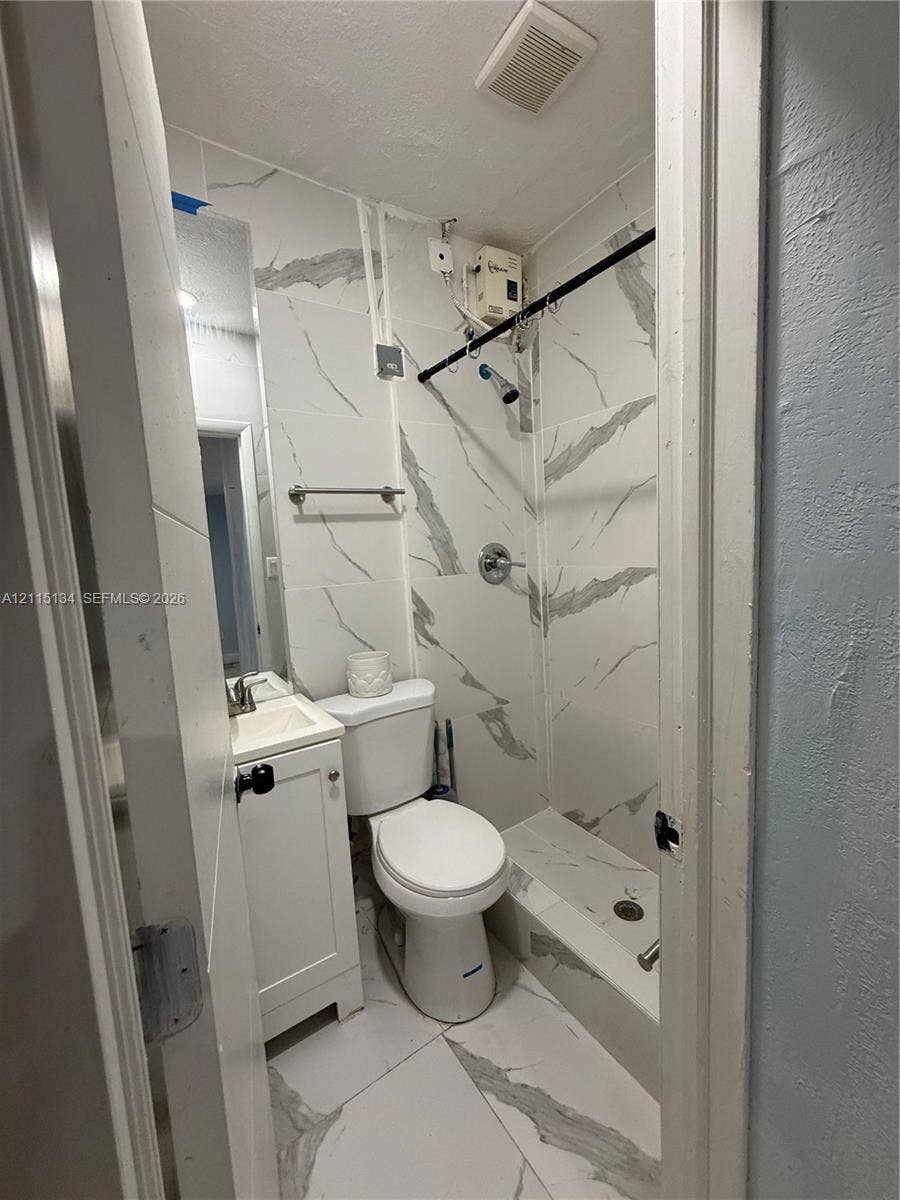 2816 SW 4th Place, #B, Fort Lauderdale, Fort Lauderdale, FL 33312 Bathroom featuring large-format, veined tile flooring and matching wall surround, white vanity cabinet with a integrated sink, and a chrome shower fixture
