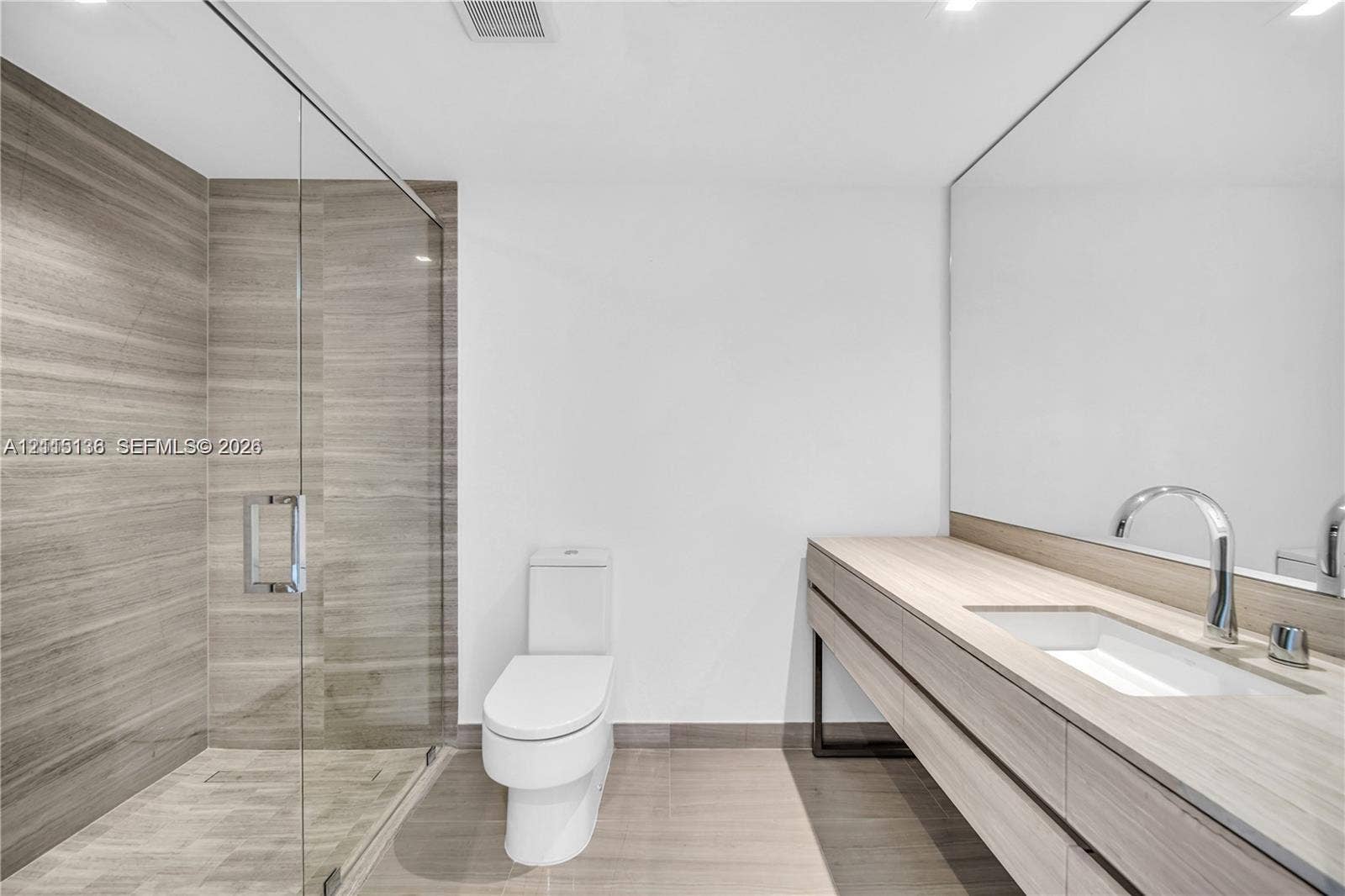 18975 Collins Avenue, #CABANA 20, Sunny Isles Beach, FL 33160 Floating vanity featuring a wood-finish cabinet and integrated sink, full-width wall mirror, glass-enclosed shower with large-format horizontal tile, and polished chrome fixtures