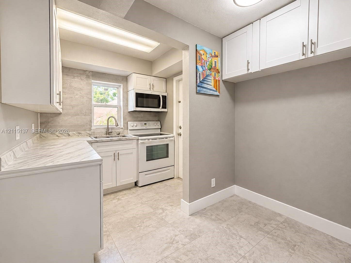 7870 SW 10th Court, #A, North Lauderdale, North Lauderdale, FL 33068 Kitchen featuring white cabinetry, solid-surface countertops, tile backsplash, built-in microwave, and large-format tile flooring
