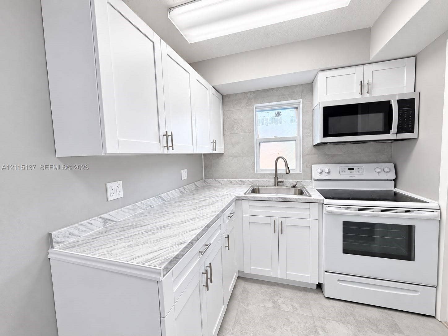 7870 SW 10th Court, #A, North Lauderdale, North Lauderdale, FL 33068 Kitchen featuring white shaker-style cabinetry, stone-patterned laminate countertops, stainless steel sink with pull-down faucet, white electric range with built-in microwave, and large-format tile backsplash