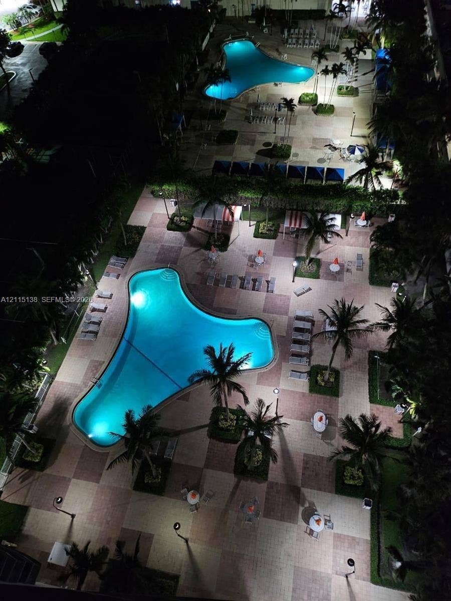 19380 Collins Avenue, #1602, Sunny Isles Beach, FL 33160 Dual swimming pools featuring tiled decking, paved walkways, palm tree landscaping, and overhead lighting