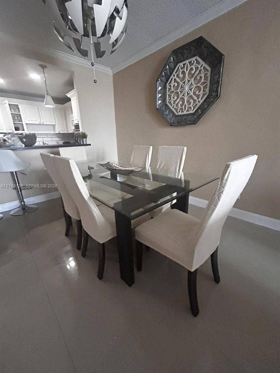 19380 Collins Avenue, #1602, Sunny Isles Beach, FL 33160 Dining area featuring large-format tile flooring, crown molding, and a contemporary multi-tiered metal chandelier