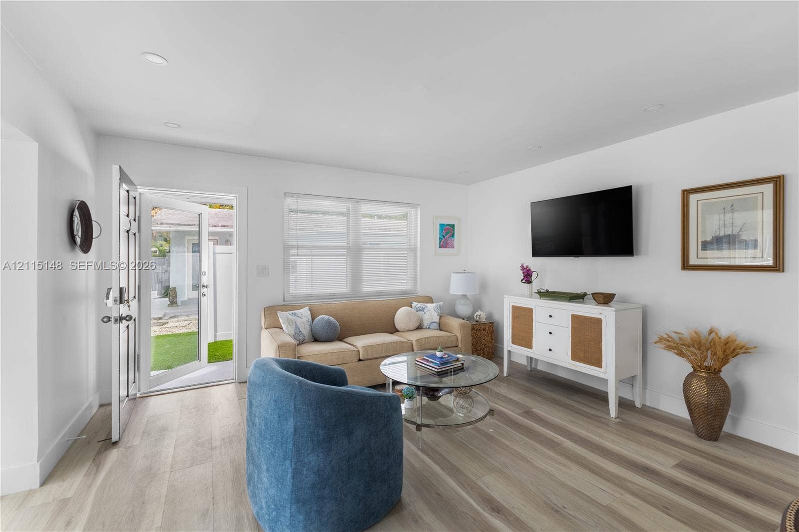 Open-concept interior featuring light-toned wood-finish flooring, recessed lighting, and a multi-pane entry door