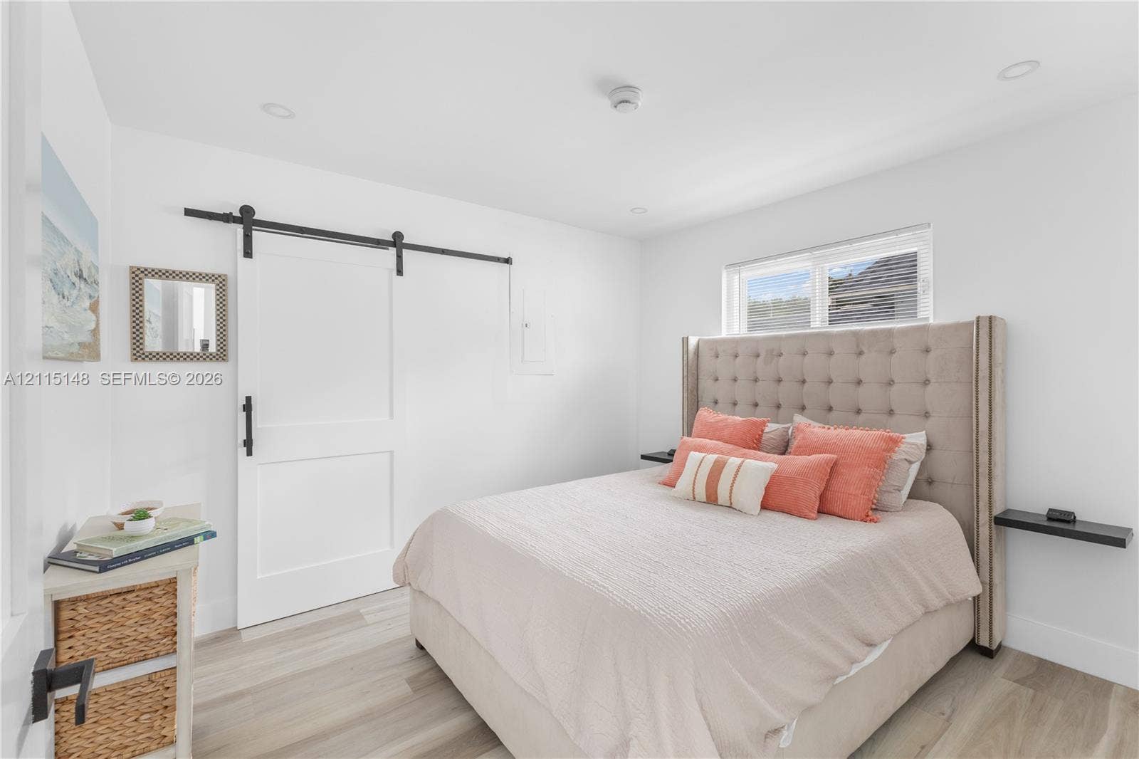 Room featuring wood-finish flooring, a white sliding barn door with matte black hardware, recessed lighting, and wall-mounted shelving
