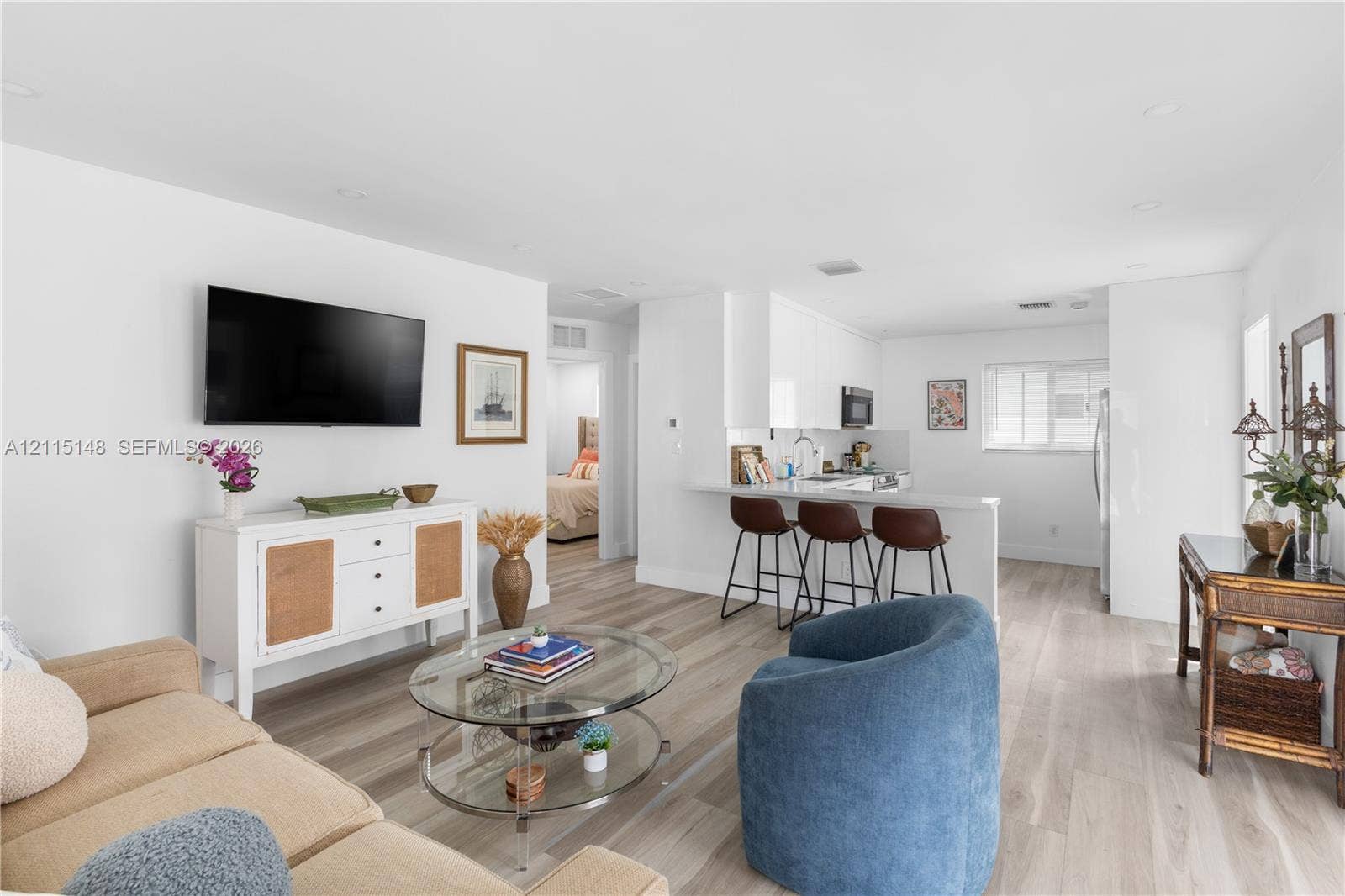 Open-concept living space featuring wood-finish flooring, recessed lighting, and a kitchen peninsula with a breakfast bar